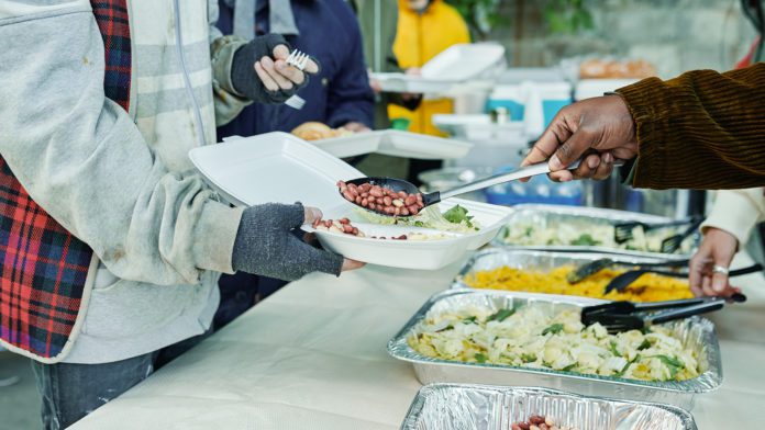 Volunteers feeding homeless people outdoors